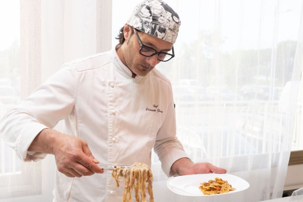 Un cuoco con la bandana impiatta le tagliatelle