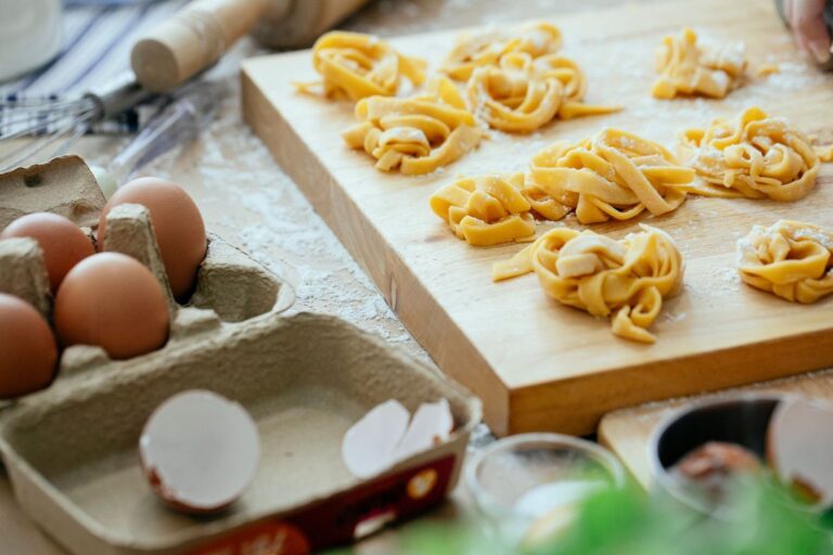 Nidi di tajarin sul tagliere, accanto alle uova