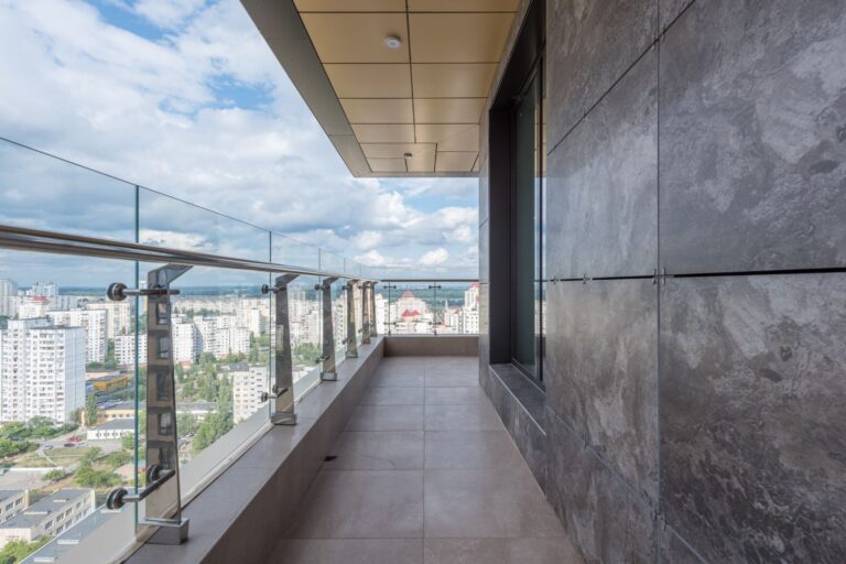 Un terrazzo con il parapetto di vetro e la città sotto, al dodicesimo piano