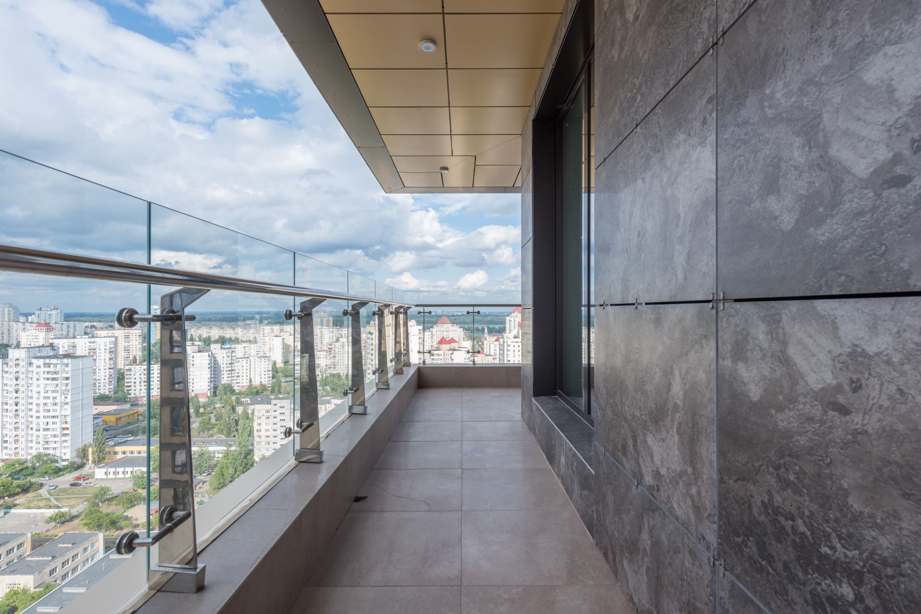 Un terrazzo con il parapetto di vetro e la città sotto, al dodicesimo piano