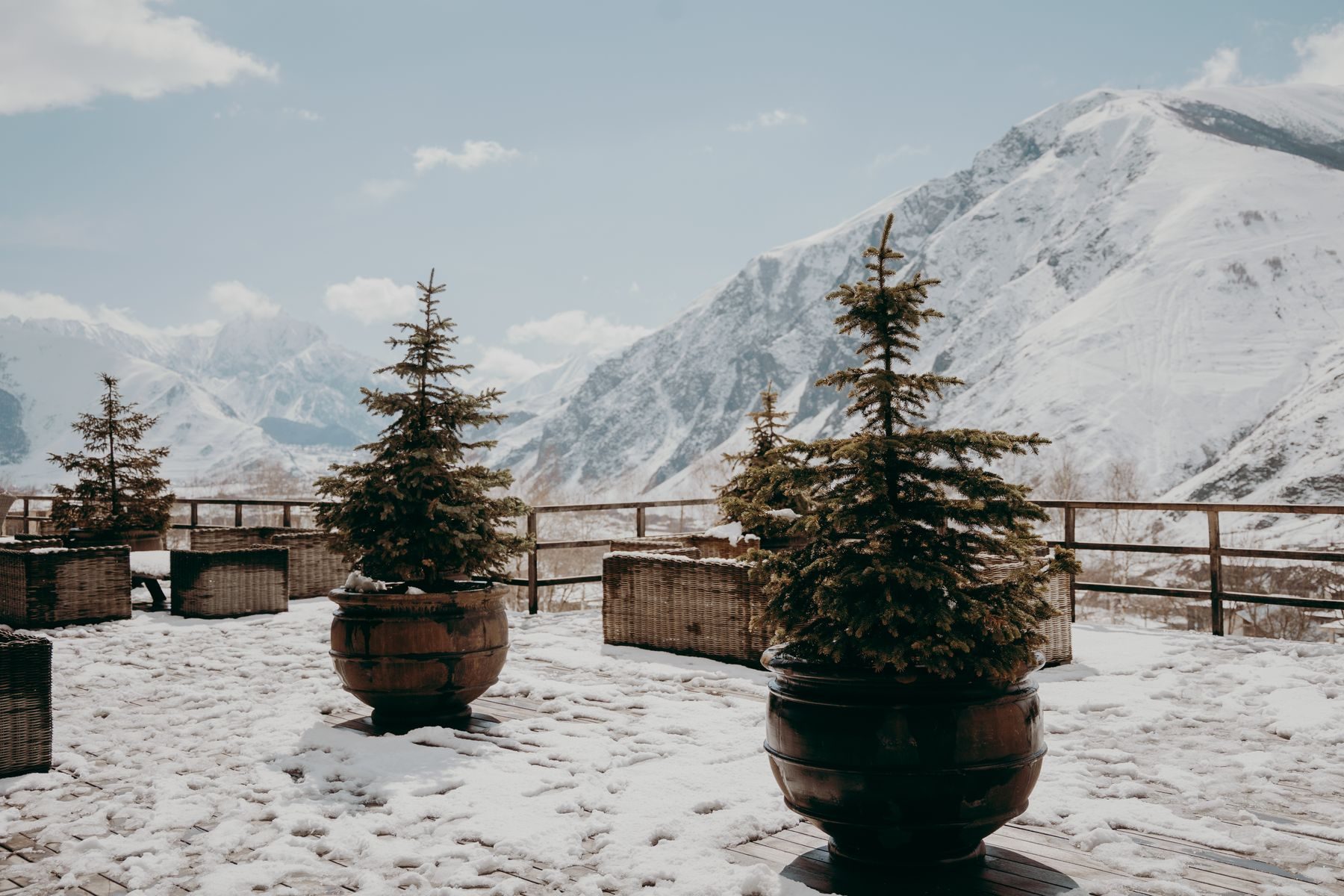 La terrazza innevata con gli abeti nei vasi e le montagne