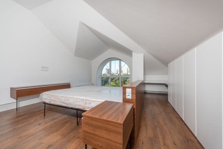 Una camera con il soffitto inclinato, il letto e gli armadi bianchi