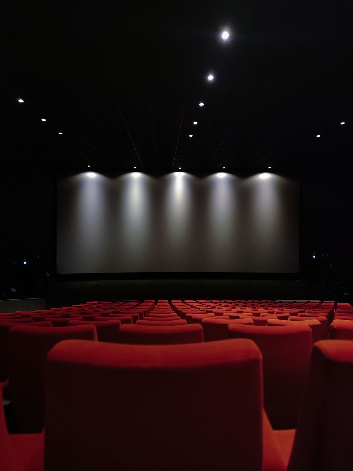 Una sala vuota con le poltrone rosse e il palco illuminato