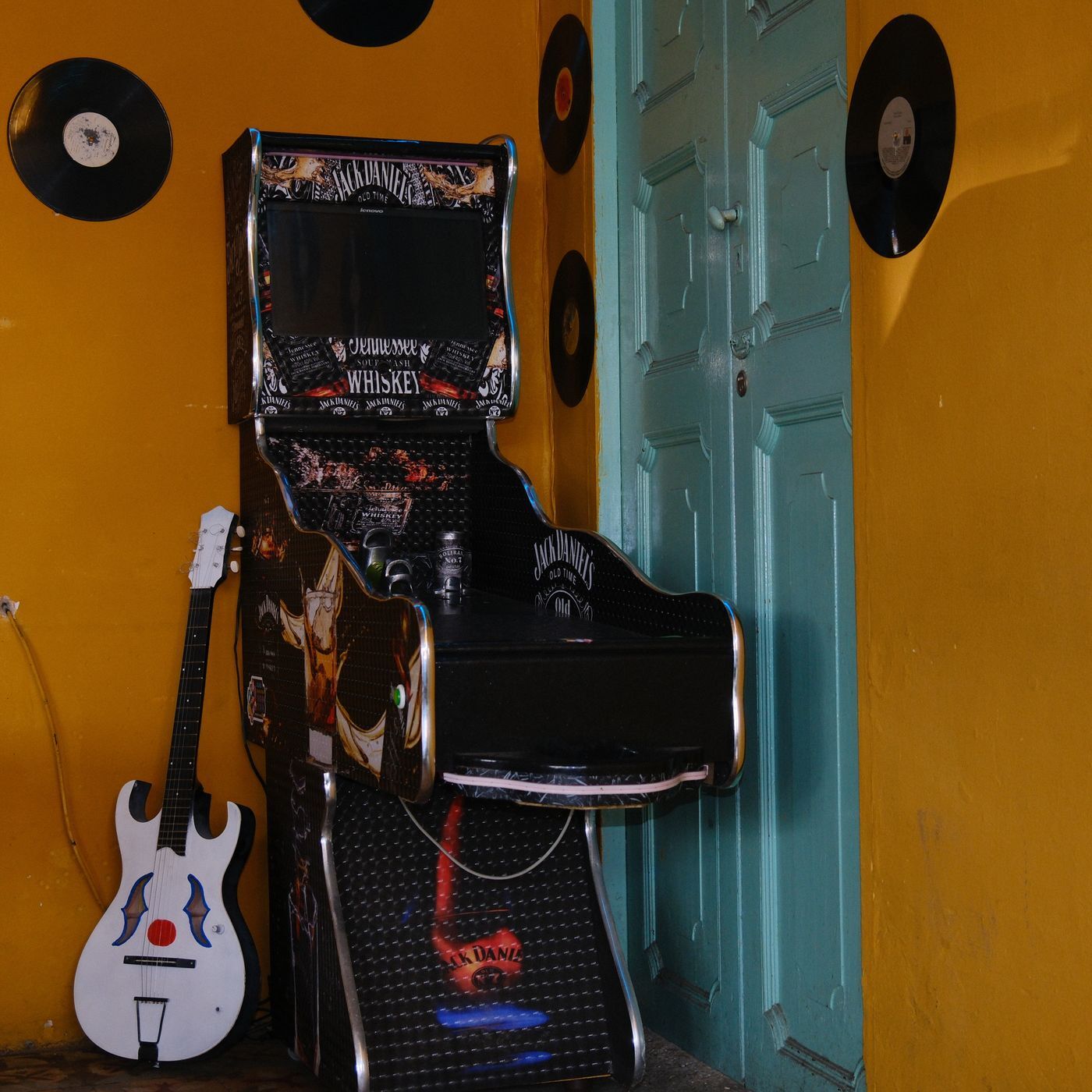 Un angolo con i dischi appesi, una chitarra e un cabinato