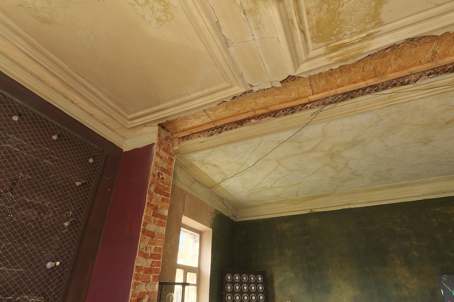 Il salone del piano nobile prima del restauro: il soffitto a stucchi con le macchie, le arelle scoperte, il pilastro in mattoni pieni e la finestra
