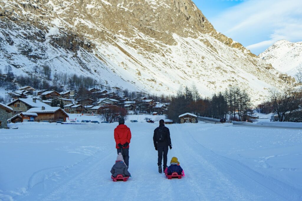 Una famiglia con gli slittini sulla strada innevata del paese