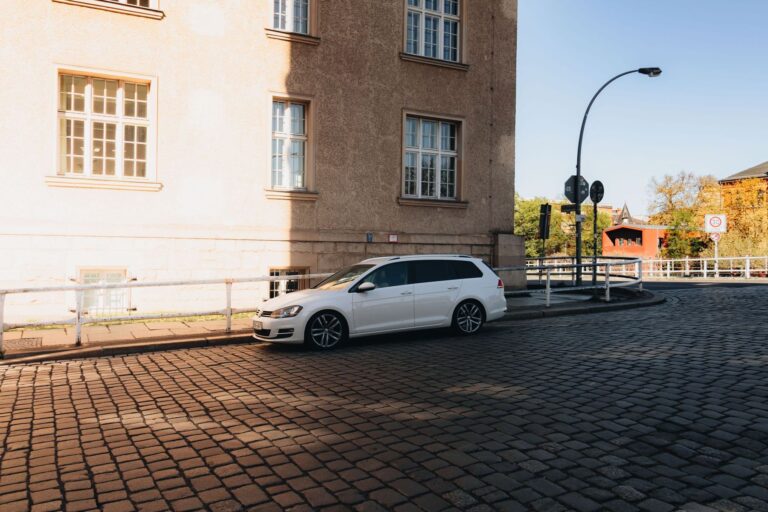 Una station wagon bianca parcheggiata in una strada col selciato